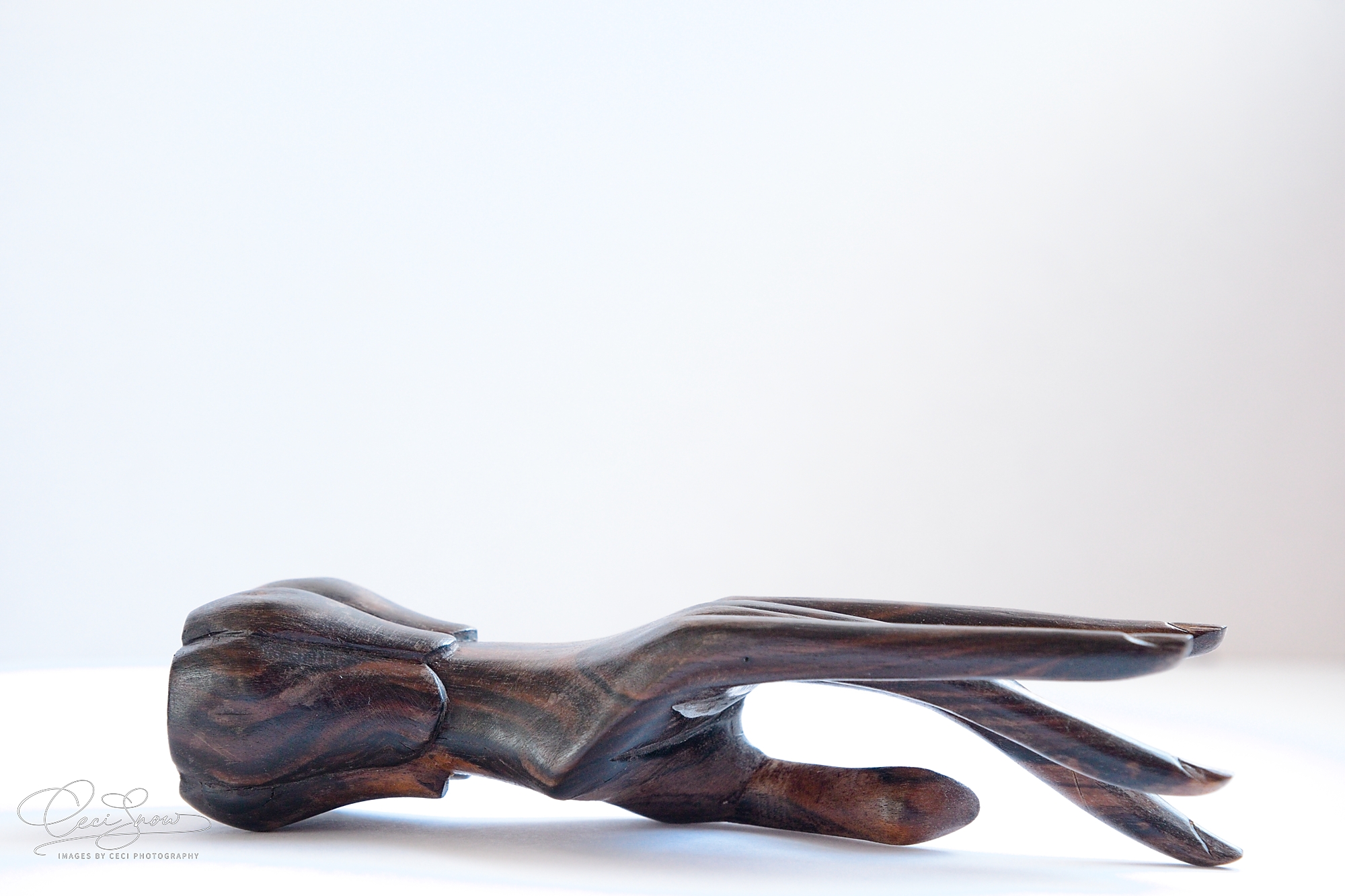 Single carved brown wooden hand resting on its side